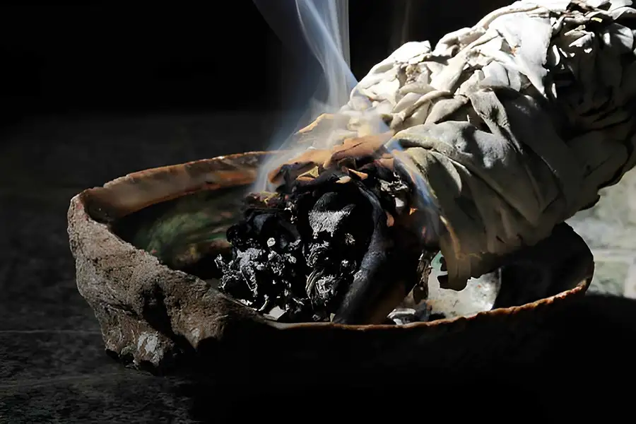 Fumigazione rituale con fascio di salvia bianca e erbe magiche